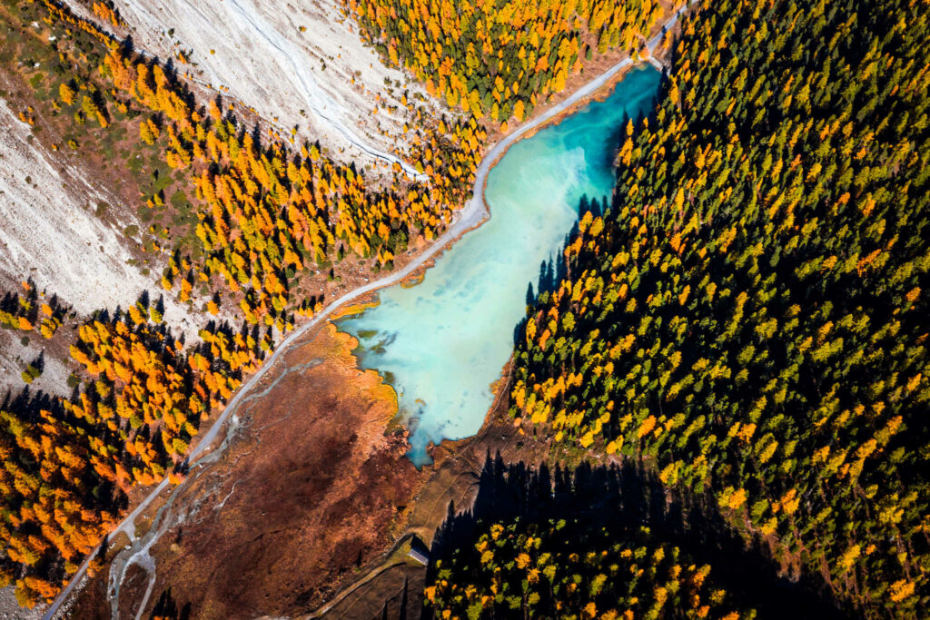 Vue aérienne en drone du Lac d'Orceyrette bleu turquoise entouré de mélèzes dorés — Aurélien Papa